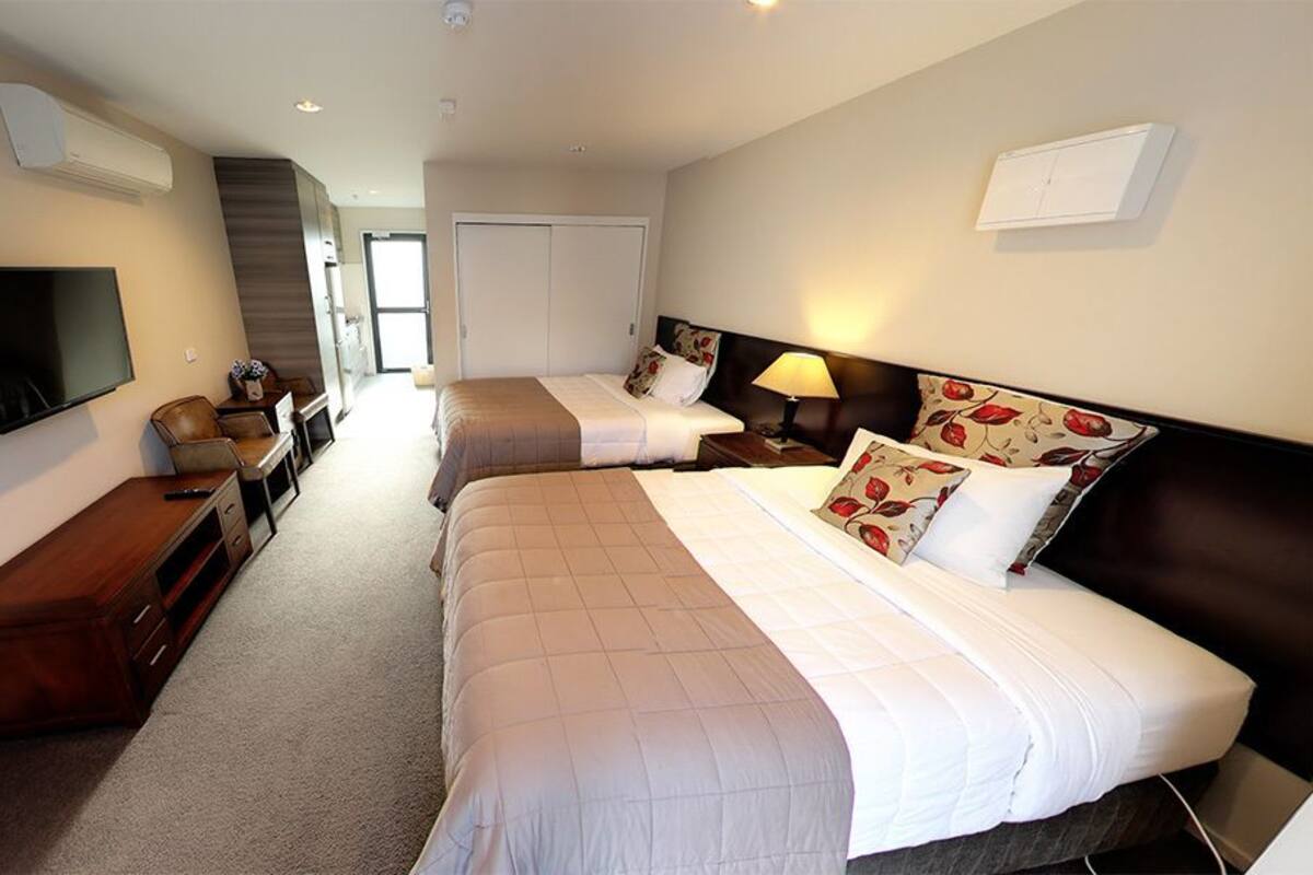 A hotel room with two beds, a TV, a desk, and a wardrobe.