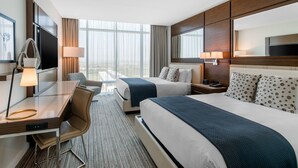 A hotel room with a large bed, a desk with a chair, a TV, and a window with curtains. - Omni Frisco Hotel at The Star (Frisco)