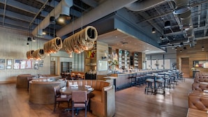 A spacious, modern bar area with a curved counter, leather seating, and industrial-style lighting. - Omni Frisco Hotel at The Star (Frisco)