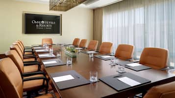 Une salle de conférence dotée d’une longue table, de fauteuils en cuir et d’un grand écran affichant le logo « OMNI Hotels & Resorts ».