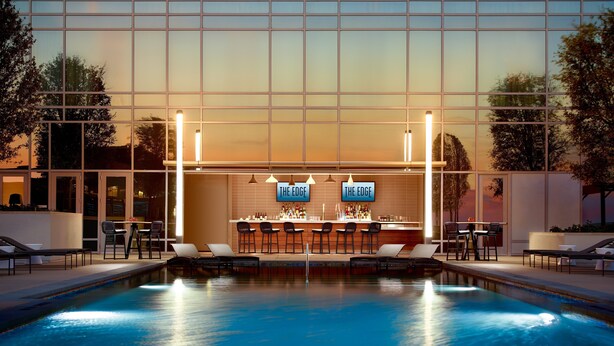 A poolside bar area with bar stools and a bar counter, surrounded by lounge chairs. - Omni Frisco Hotel at The Star (Frisco)