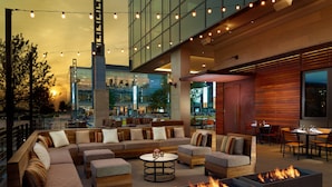 An outdoor seating area with sofas, a round table, and built-in fire pits. - Omni Frisco Hotel at The Star (Frisco)