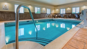 An indoor swimming pool with a no diving sign, poolside chairs, and a lifeguard chair.