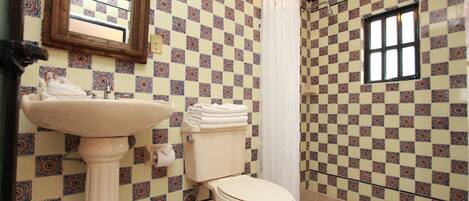 A bathroom with a toilet, sink, and a window.