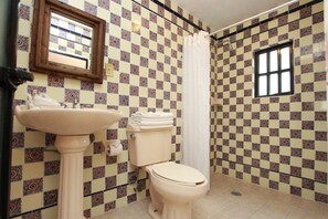 A bathroom with a toilet, sink, and a window. - Hotel Mesón del Rosario (Guanajuato)