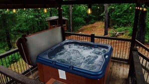 A hot tub on a wooden deck with a forest view.