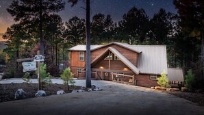 A rustic cabin with a sloped roof, a wooden exterior, and a metal awning. There is a sign indicating the name "The Night Sky" and a phone number.