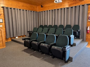 A cinema room with rows of seats, a projector, and curtains.