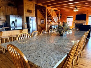 A spacious kitchen with granite countertops, wooden chairs, a dining table, and a staircase leading to a loft area. - Mountain Views + Theater, Game Room & Hot Tub - Free Daily Activities (Sevierville)