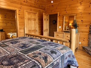 A wooden cabin bedroom with a bed, dresser, and a mirror.