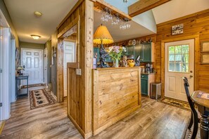 Un interior de madera con una zona de cocina, una mesa de comedor y una puerta con ventanal.