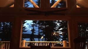 Eine Holzhütte mit großem Fenster mit Blick auf einen bewaldeten Bereich im Abenddämmerung.