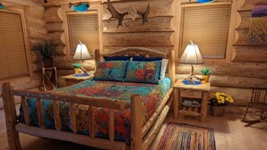Ein schlafzimmer im Chalet-Stil mit einem hölzernen Bett, zwei Nachttischlampen, einem Teppich und dekorativer Wandgestaltung.