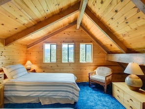 A cozy wooden cabin bedroom with a bed, chair, bedside table, and windows. - Crow`s Nest - Fun Treetop Design (Leavenworth)
