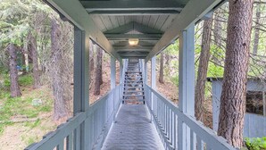 A wooden covered walkway with railings, surrounded by trees.