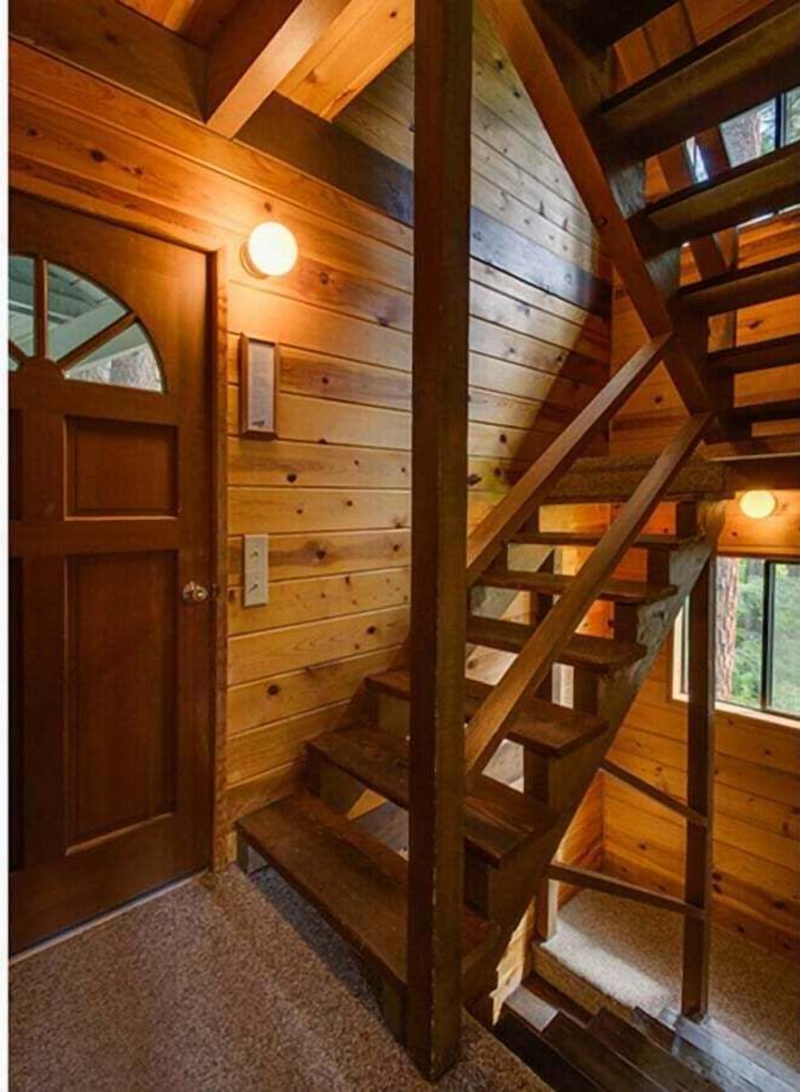 A wooden staircase leading to a lofted area with a door and a light fixture.