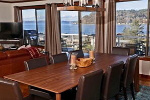 A dining area with a wooden table, chairs, and a view of a lake and mountains.