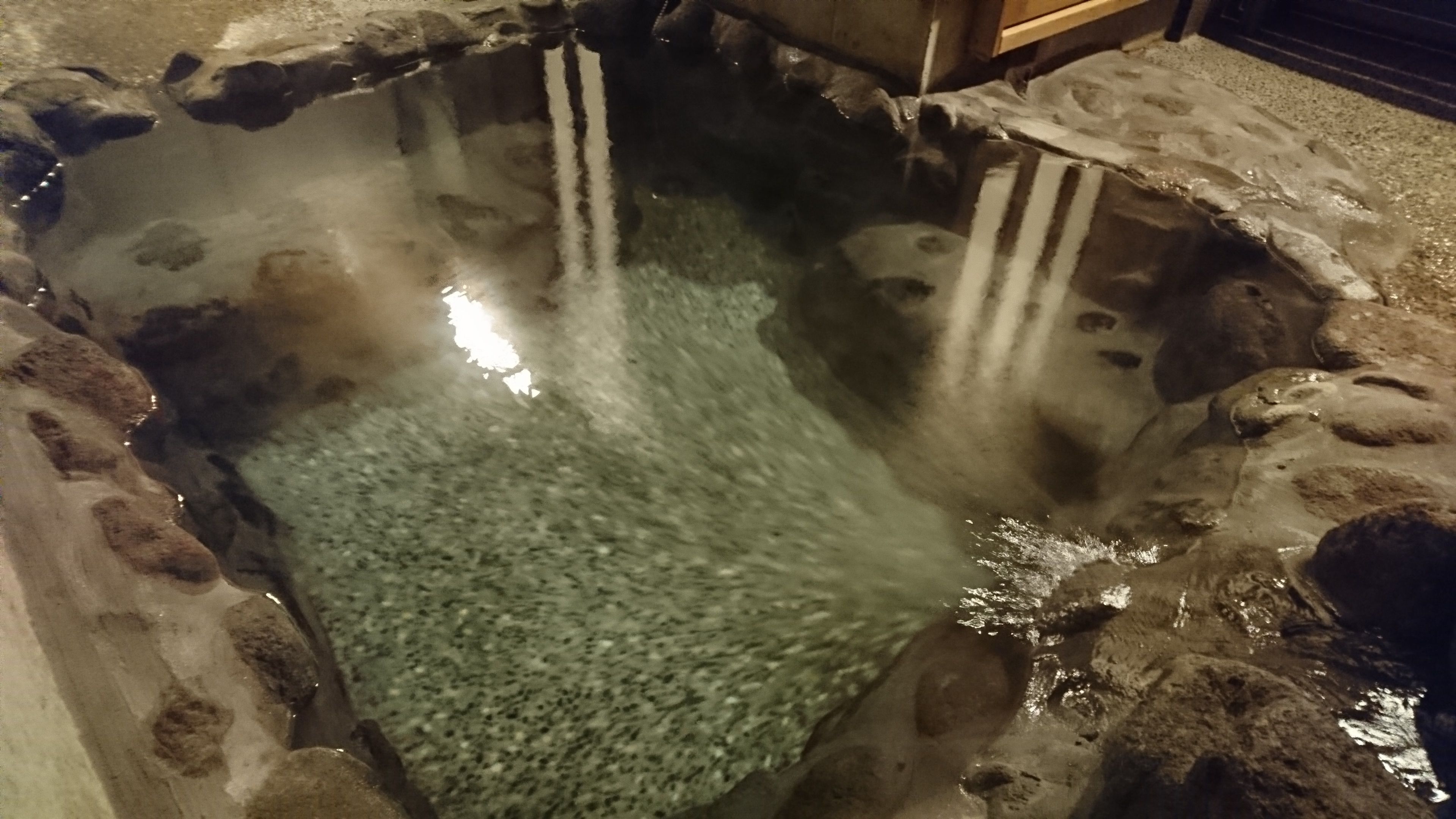 Un manantial de agua caliente con aguas cristalinas, rodeado de muros de piedra.