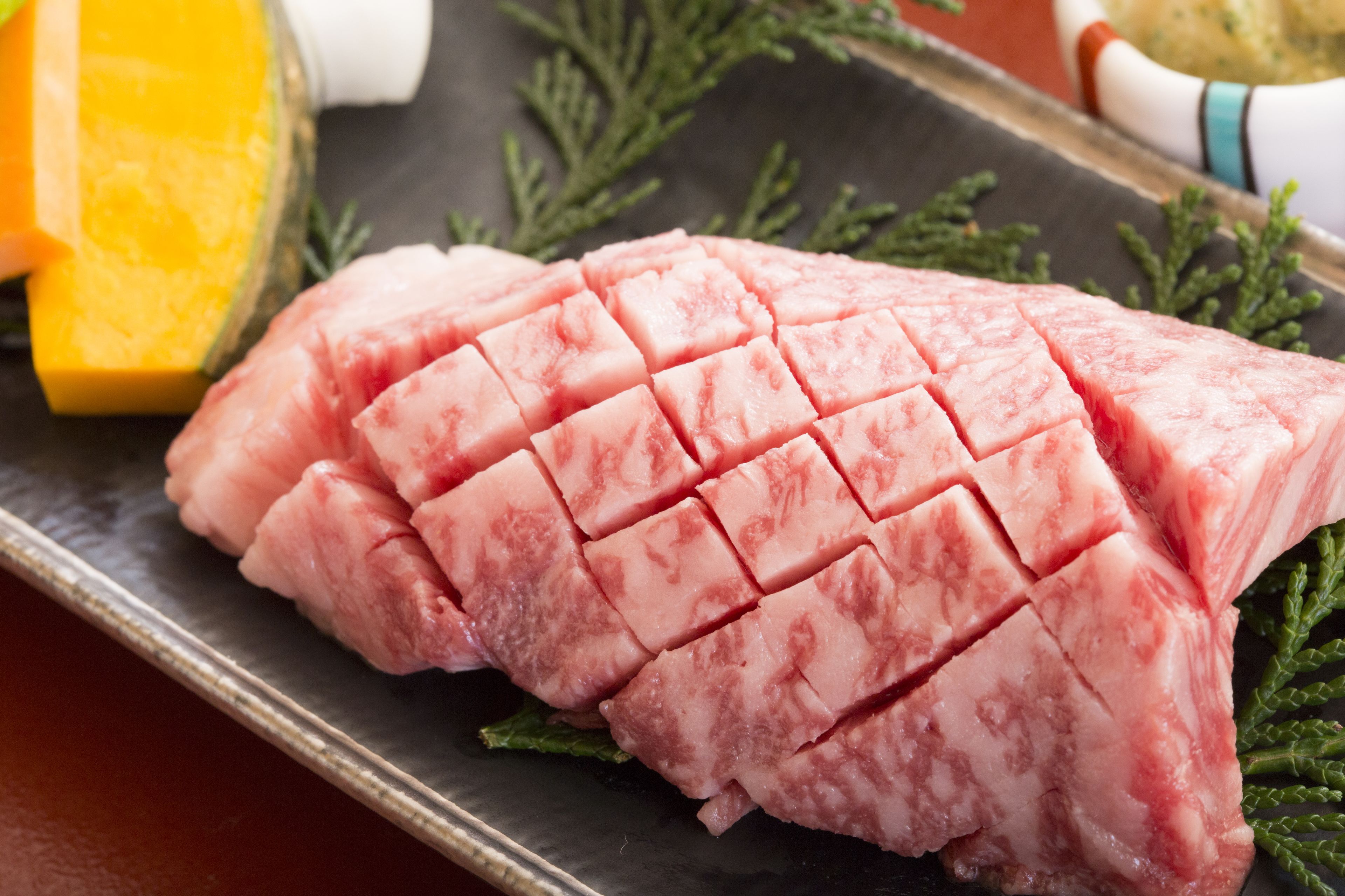 Une portion de viande crue présentée sur une assiette, avec un décor en arrière-plan.