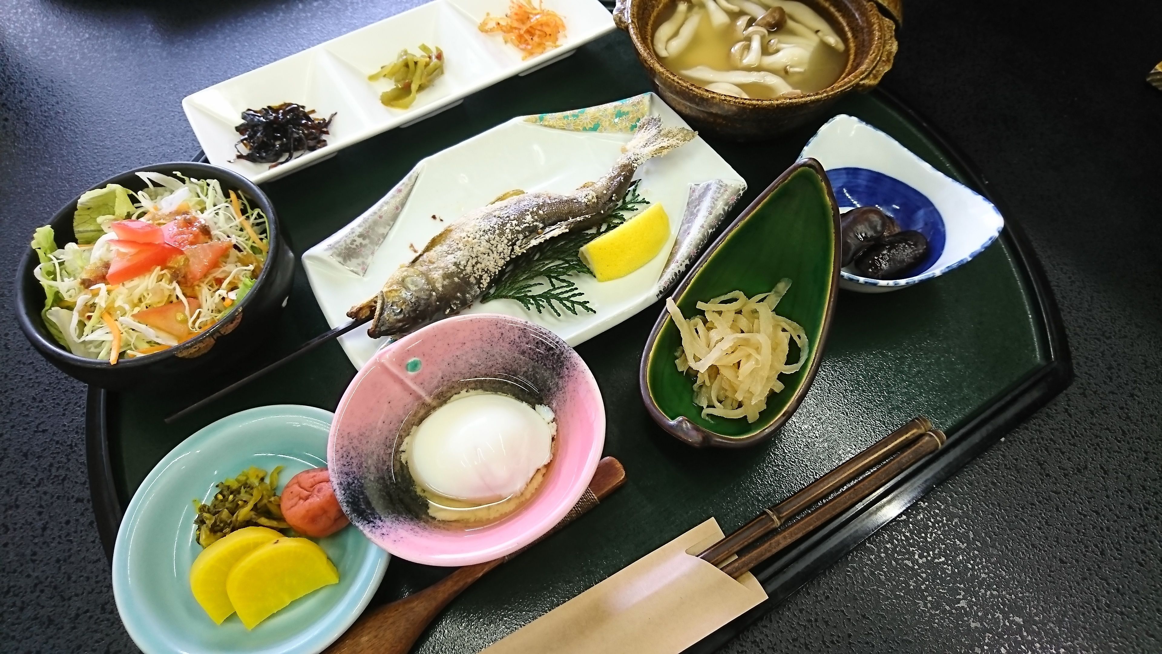 A variety of dishes including a fish, vegetables, and a bowl of soup on a tray.
