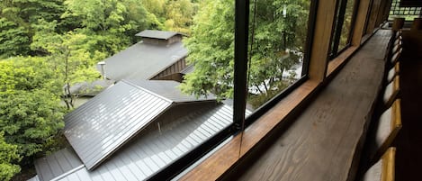 A traditional Japanese room with tatami flooring, a sliding door, and a view of a forested area.