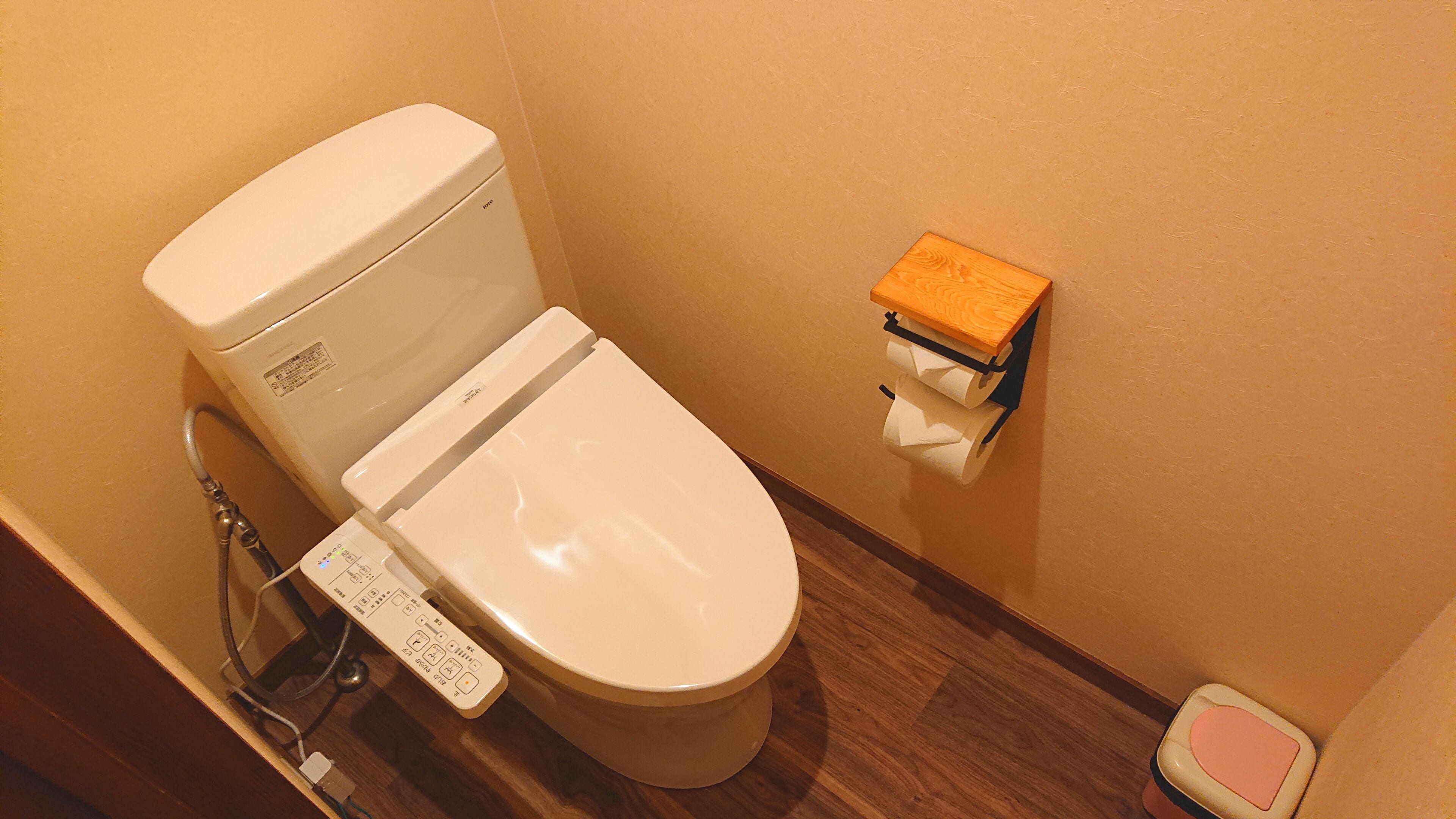 A toilet with a control panel, a toilet paper holder, and a bidet.