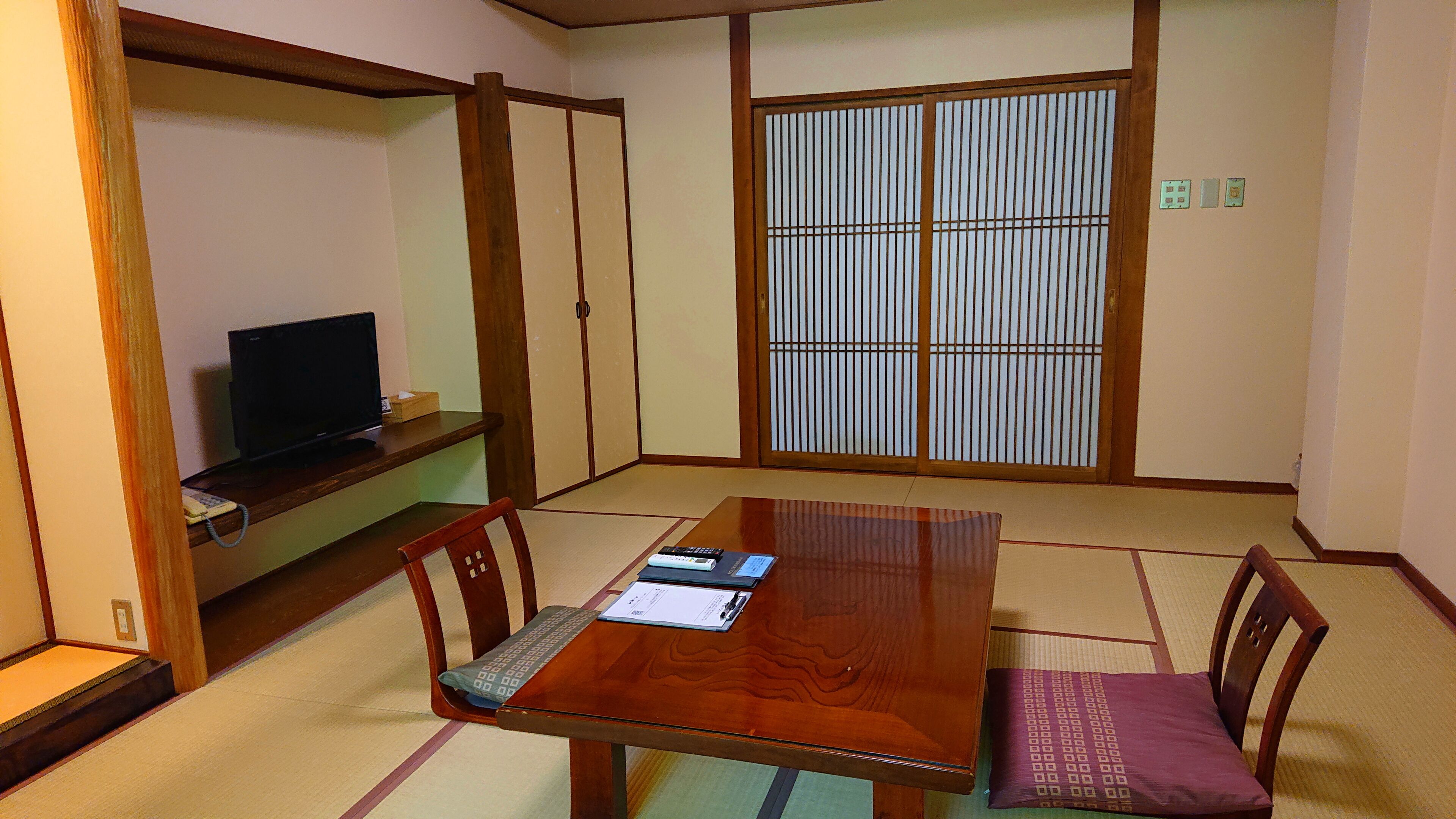 A traditional Japanese-style room with tatami flooring, a wooden table, and sliding shoji doors.