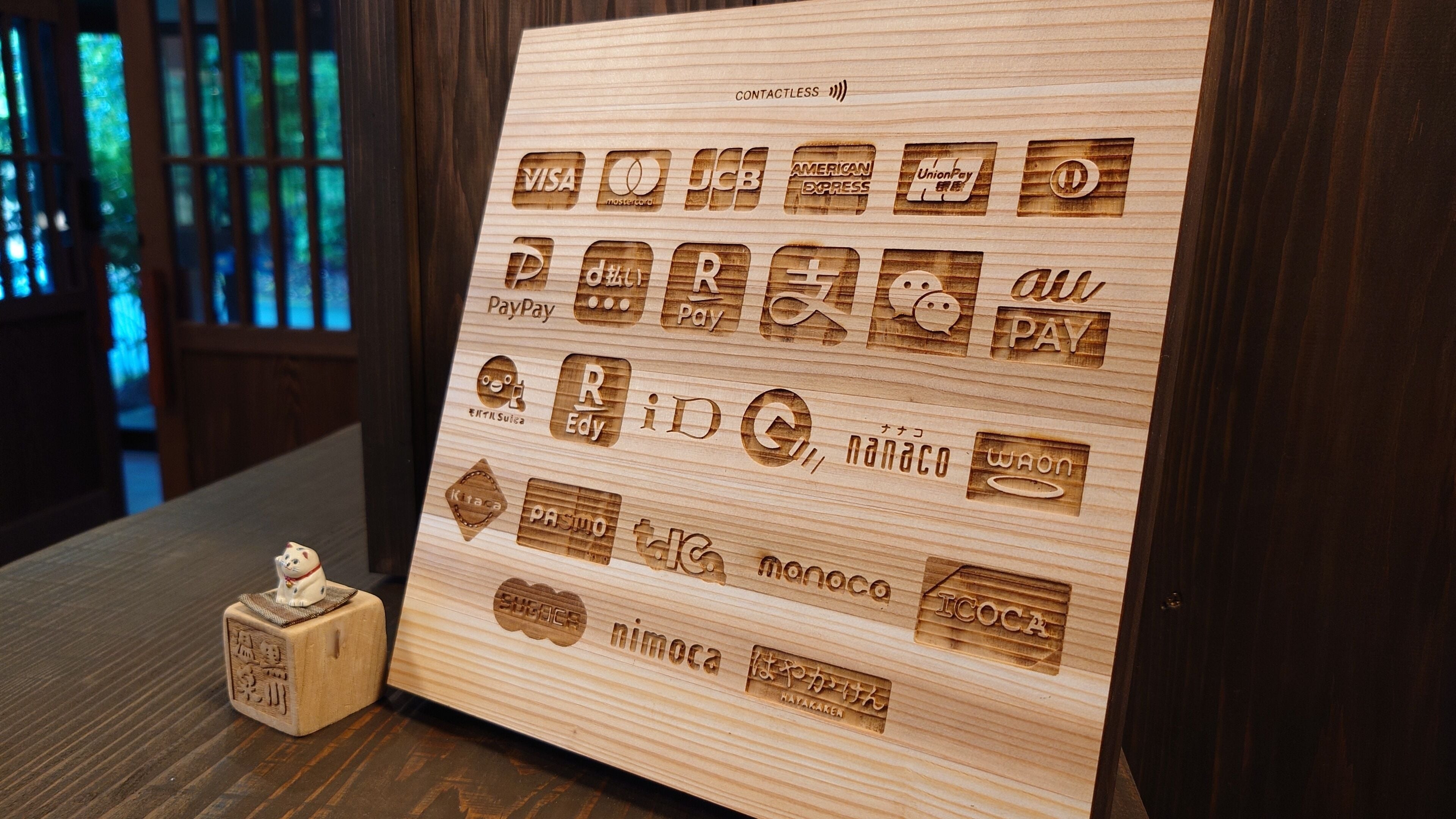 Una tabla de madera con logotipos de diversos métodos de pago, incluyendo VISA, MasterCard y PayPal.