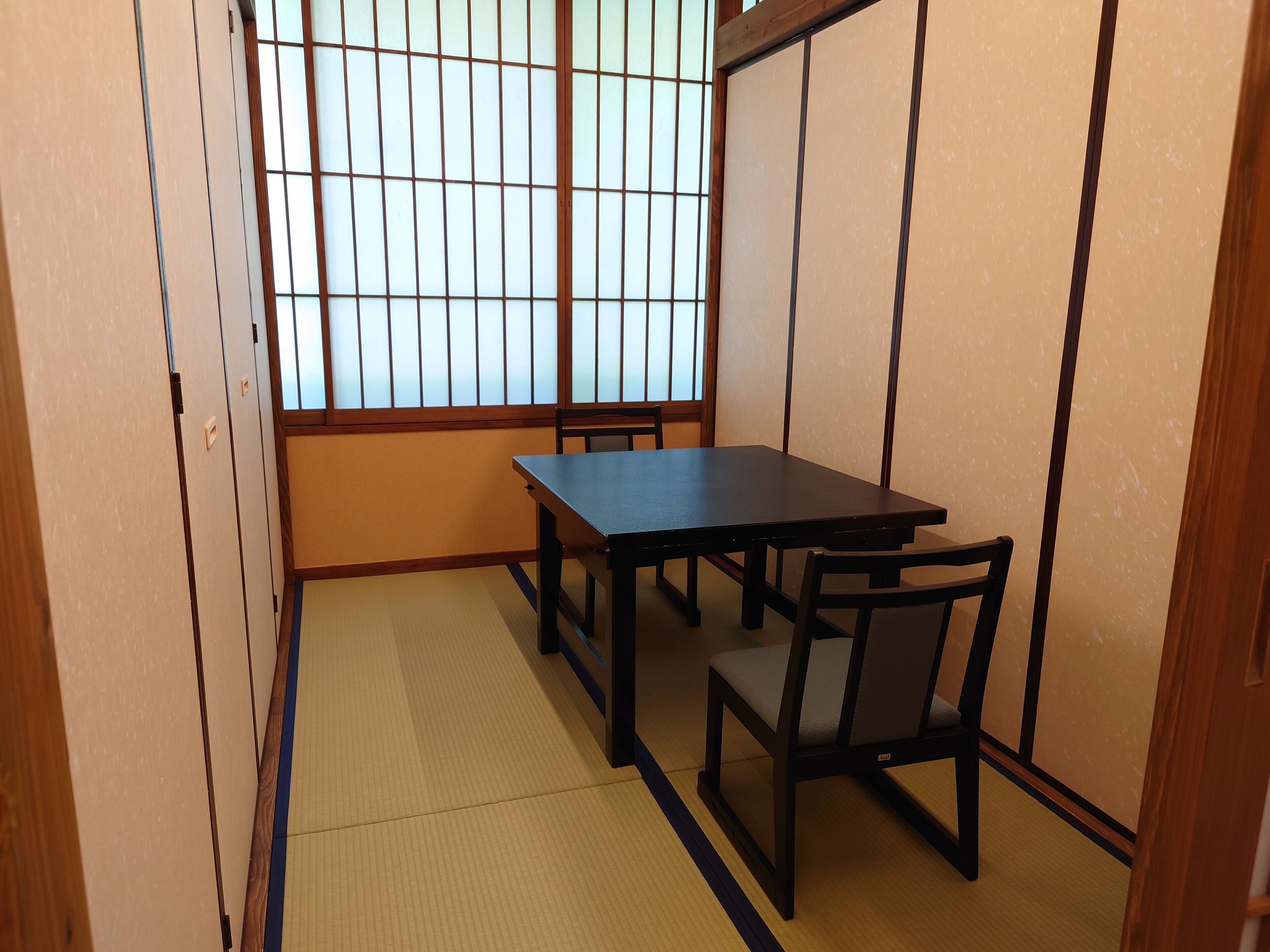 A traditional Japanese room with tatami flooring, a low table, and a sliding door.