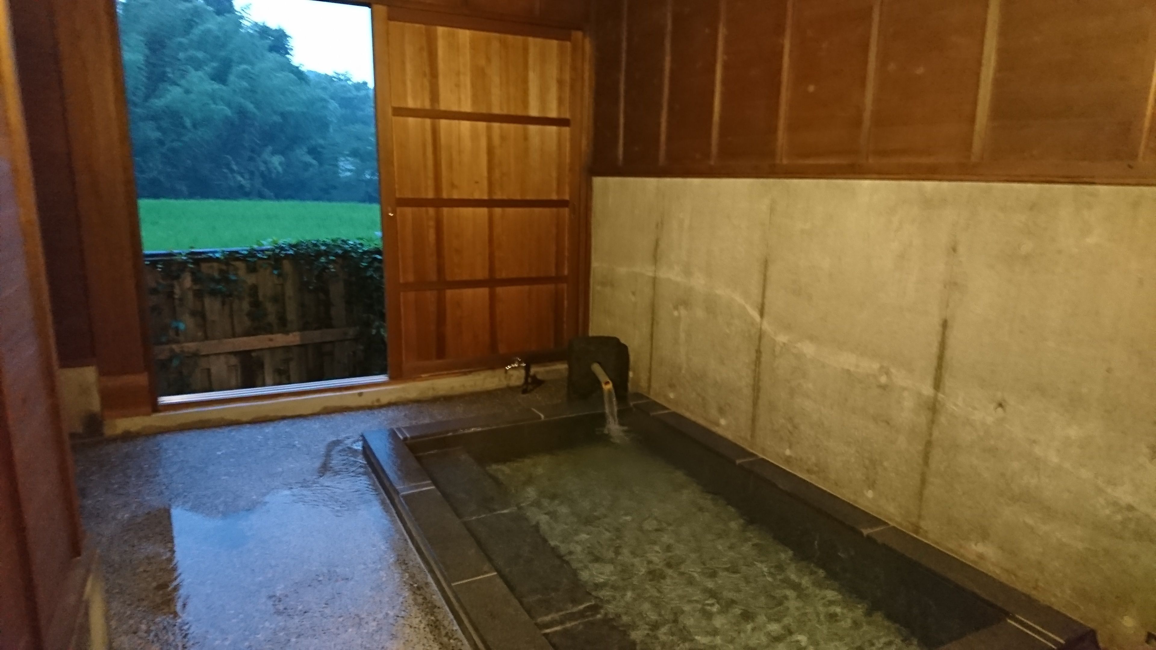 Une pièce de style japonais traditionnel, avec un sol recouvert de tatamis, une porte en bois et un petit lavabo doté d’un robinet.