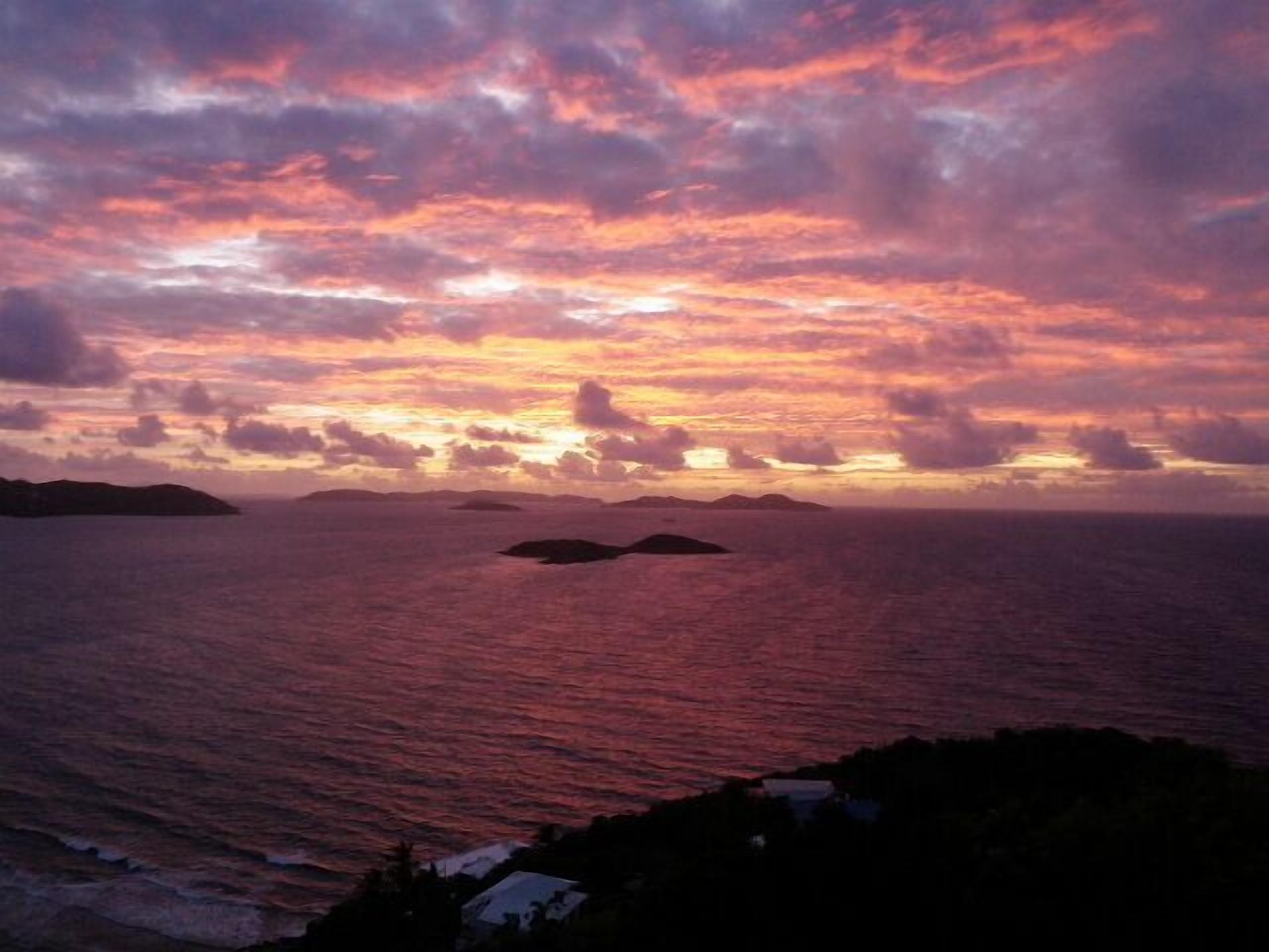 Un coucher de soleil sur l’océan, avec des îles lointaines à l’horizon.