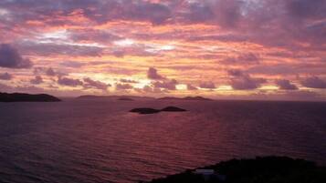 Un coucher de soleil sur l’océan, avec des îles lointaines à l’horizon.