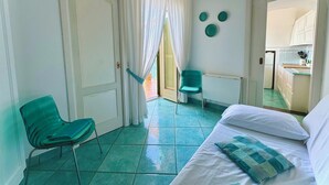 Ein Hotelzimmer mit Bett, Stuhl, kleinem Tisch und Blick zur Küche.
