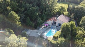 An aerial view of a house with a swimming pool, surrounded by dense forest. - Secluded villa with large garden pool
Overlooks beautiful picturesque
village (Soubès)