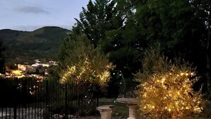 A garden pathway with decorative lights, a metal fence, and a view of buildings in the background. - Secluded villa with large garden pool
Overlooks beautiful picturesque
village (Soubès)