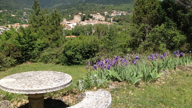 A stone table and bench in a garden with purple flowers and a view of a village in the distance. - Secluded villa with large garden pool
Overlooks beautiful picturesque
village (Soubès)