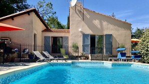 A swimming pool with lounge chairs and umbrellas, a building with a tiled roof, and a satellite dish. - Secluded villa with large garden pool
Overlooks beautiful picturesque
village (Soubès)