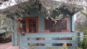 A two-story house with a light blue exterior, wooden shutters, and a front porch with benches. - An off-grid cabin for two, with views of the Els Ports Mountain range   (Tivenys)