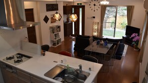 A modern kitchen with a central island, a dining area with a table and chairs, and a living room with a sofa and TV. - The Pool Resort Villa Hasta Manana (Onna)