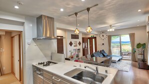 A modern kitchen with a large island, stainless steel appliances, and pendant lighting. - The Pool Resort Villa Hasta Manana (Onna)