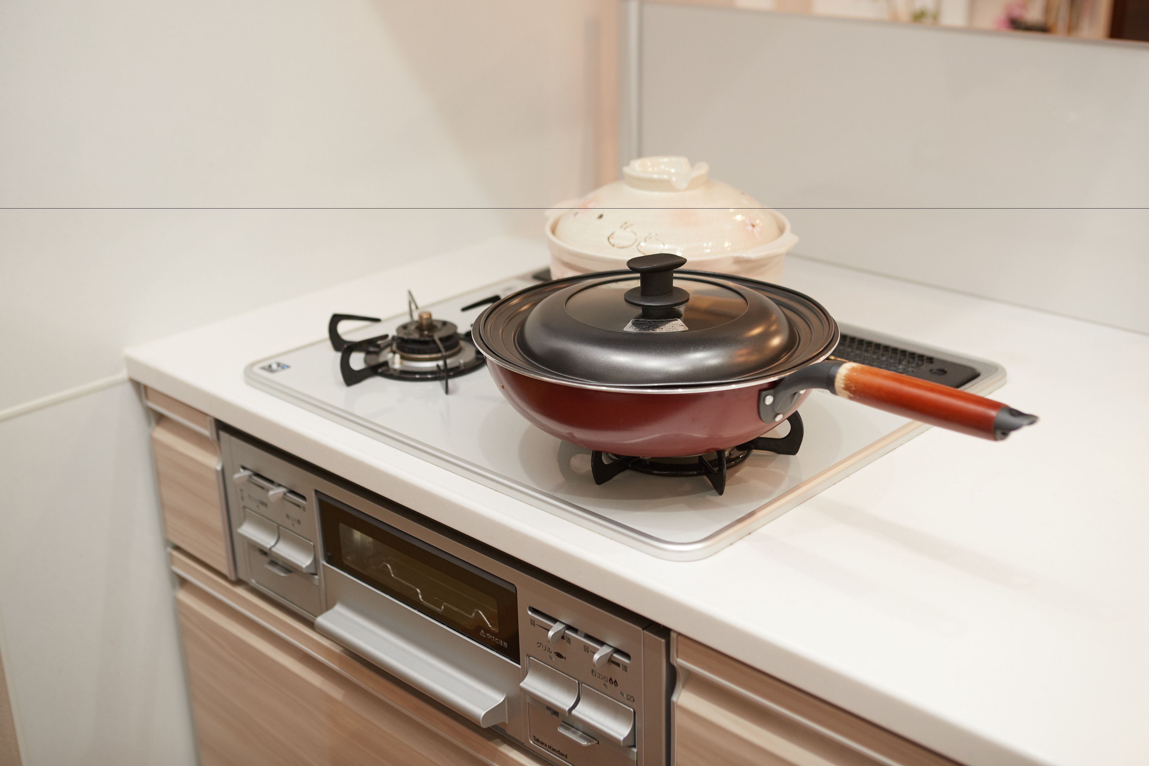 Una cocina compacta con estufa a gas, una olla en la hornalla y un horno moderno debajo.