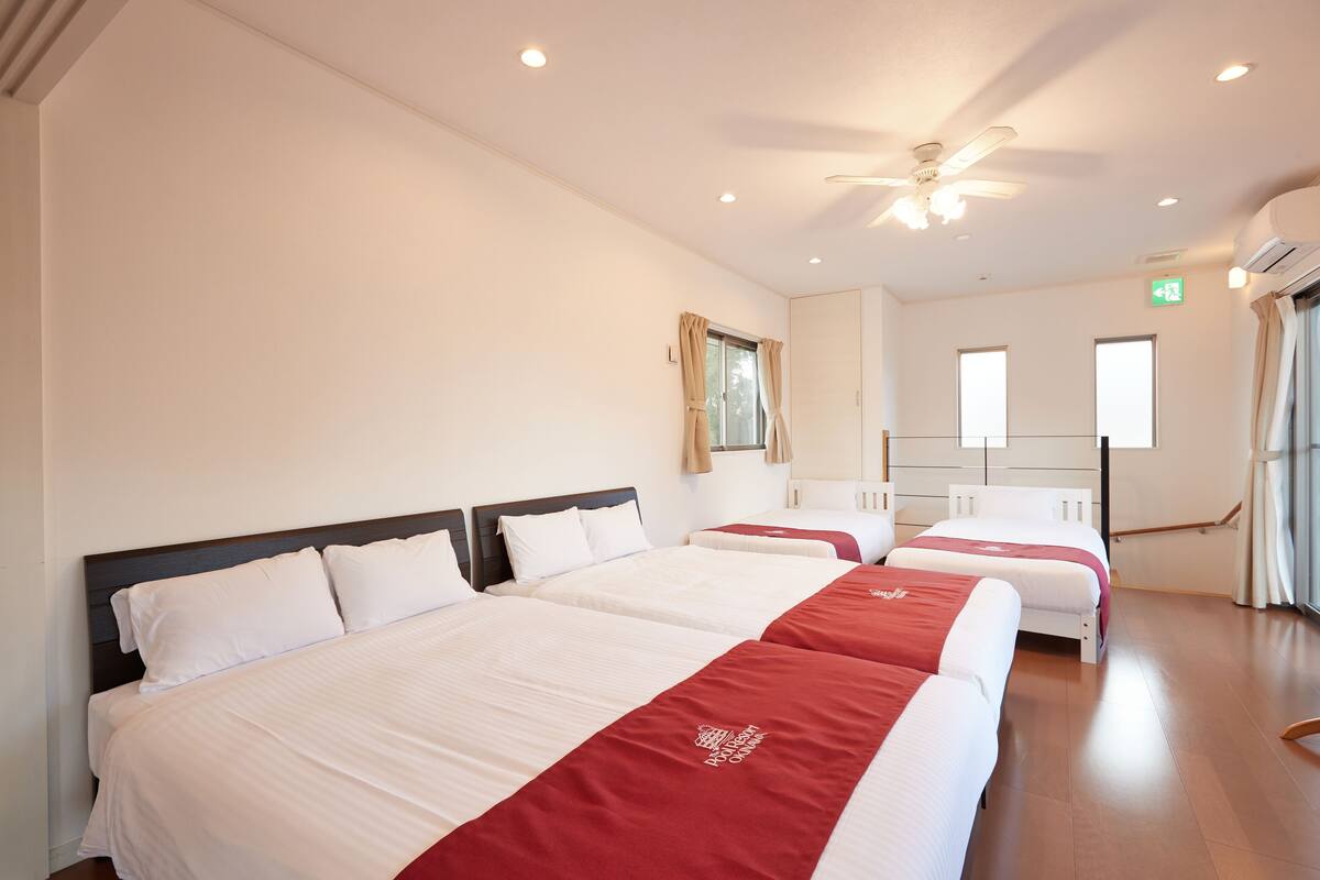 A hotel room with two beds, a ceiling fan, and a window.