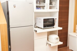 A compact kitchen with a white refrigerator, a microwave, and a rice cooker on a shelf. - The Pool Resort Villa Hasta Manana (Onna)