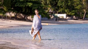 Une scène de plage avec une eau claire et une personne qui se promène.