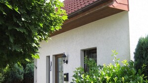 A house with a red-tiled roof, a white exterior wall, and a brick pathway leading to the entrance. - Holiday house, WiFi, close to the beach, max. 6 people, 80sqm, 3 bedrooms, barbecue area  (Butjadingen)