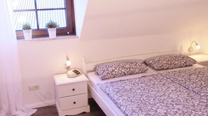 Cozy retreat with a single bed, bedside table, and potted plants.