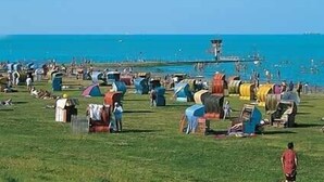 A campsite with tents and a lighthouse in the background. - Holiday house, WiFi, close to the beach, max. 6 people, 80sqm, 3 bedrooms, barbecue area  (Butjadingen)