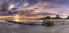 A beach with a pier extending into the water, surrounded by rocks and vegetation.