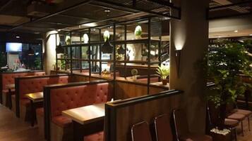 A restaurant with booths and tables, wooden partitions, and potted plants.