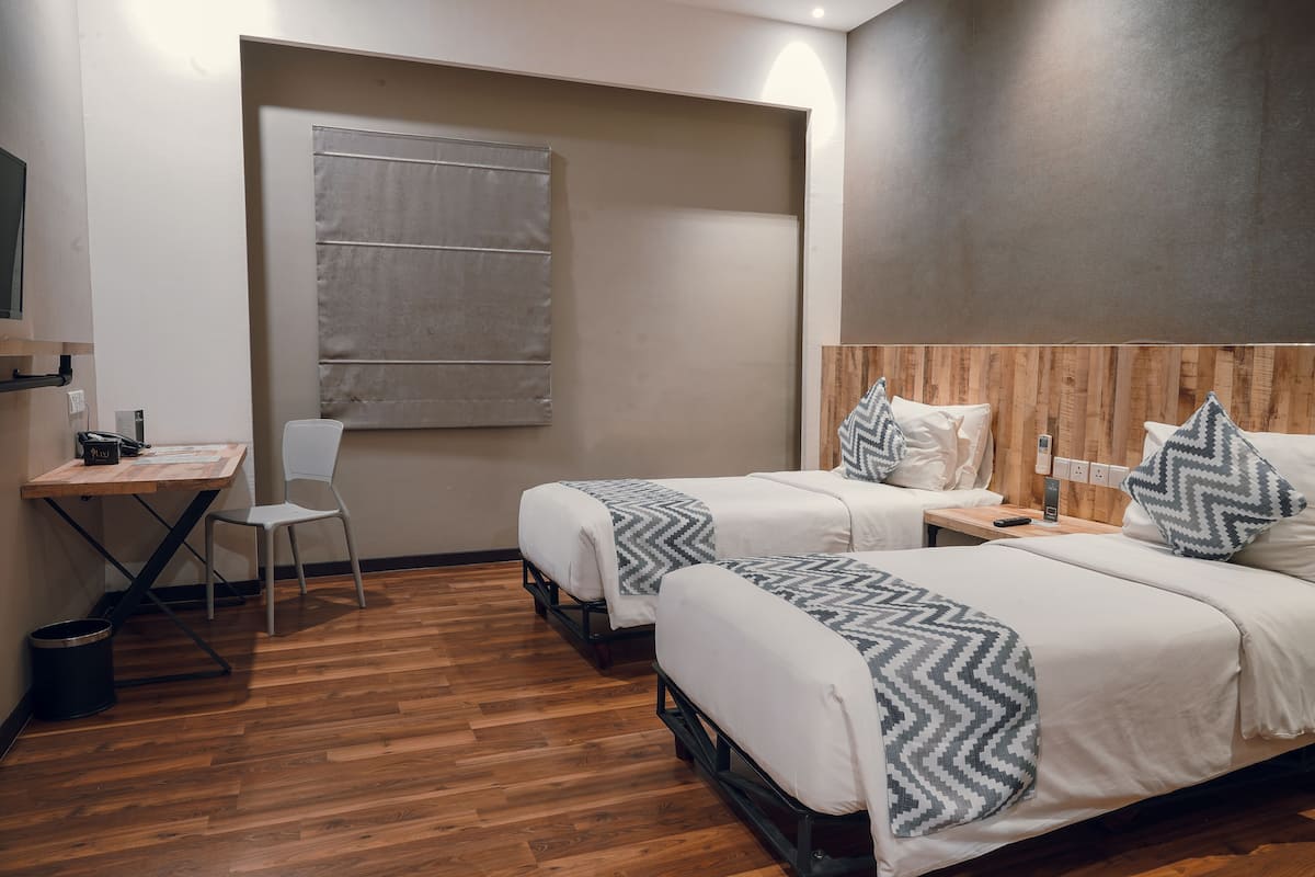 Une chambre d’hôtel avec deux lits, un bureau, une chaise et un plancher en bois.